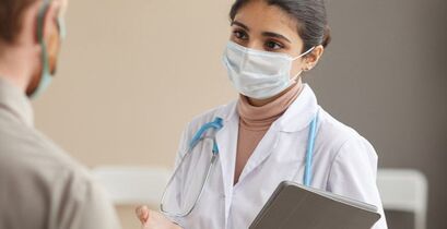 masked health care provider speaking with patient
